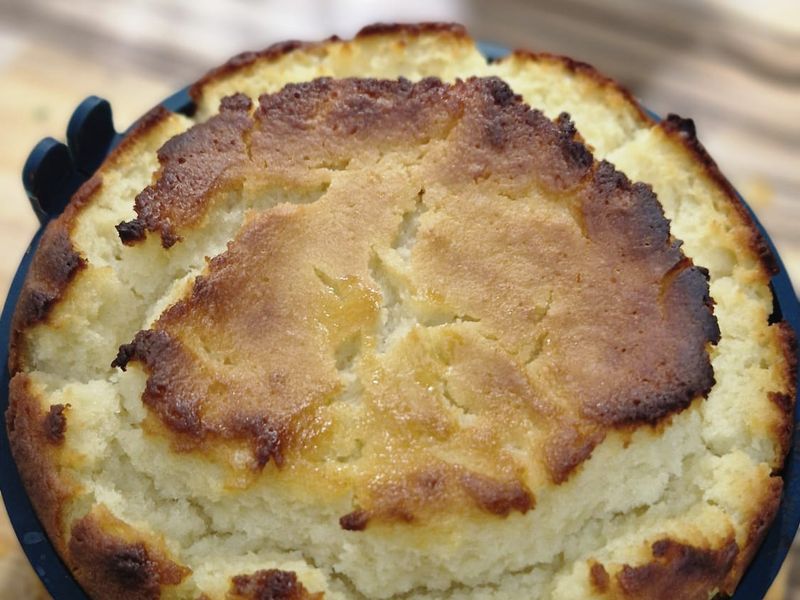 A golden home-baked cake, fresh out of the oven, in a blue baking tin